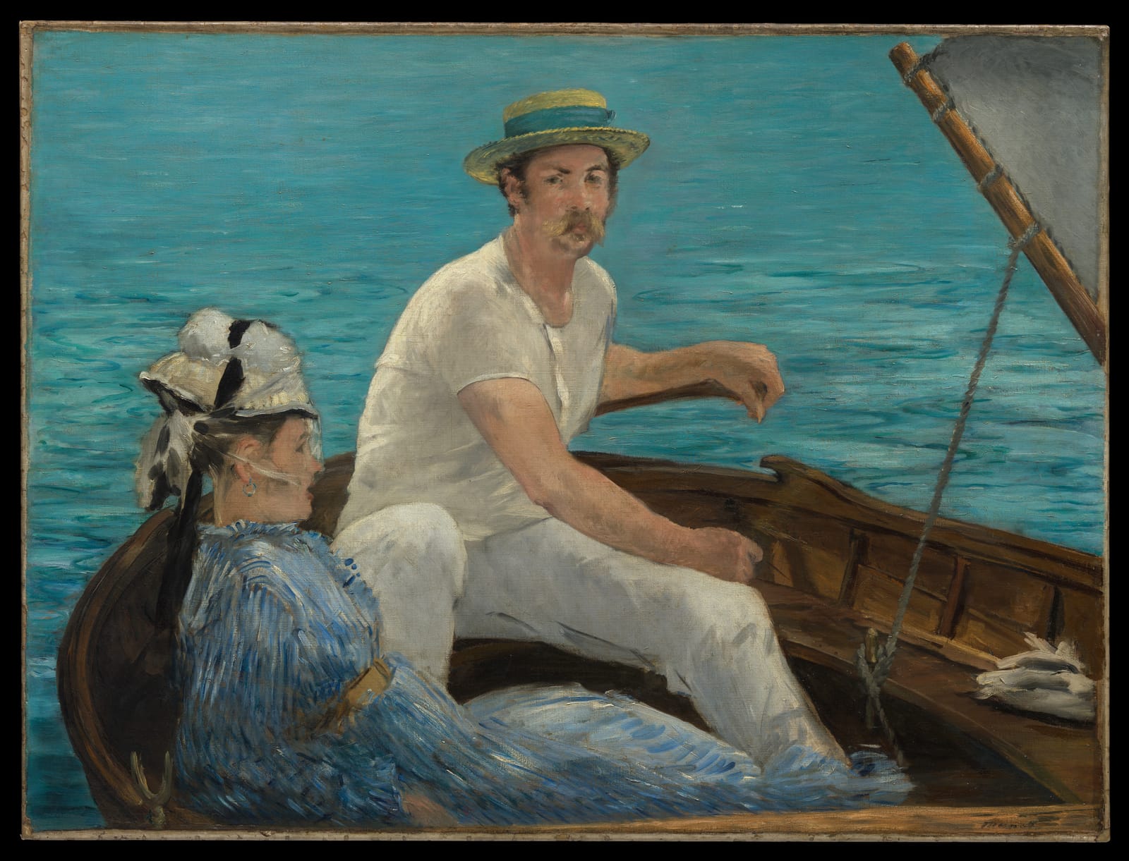 A man in white and a woman in a blue dress sit in a sailing boat on bright blue water.