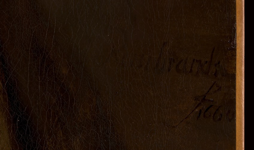 The inscription “Rembrandt f. 1660” in dark paint on the dark background, close up.